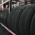 Rows of new car tires on storage racks in a shop, with a close-up of the tread patterns.
