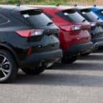 Rear view of multiple Ford Escape SUVs parked in a dealership lot, illustrating the availability of modern pre-owned and certified vehicles in various exterior colors.