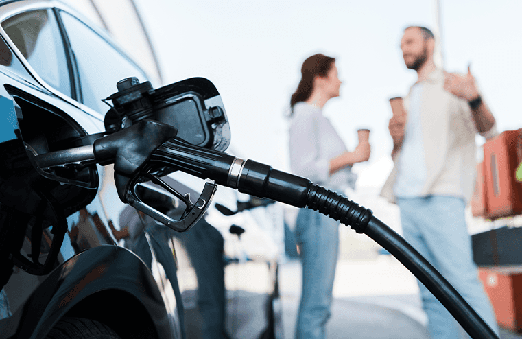 What Type of Gas is Best for My Car? | Giambalvo Chrysler Dodge Jeep RAM in York, PA | Close up of gas nozzle pumping gas while couple is talking in the background 