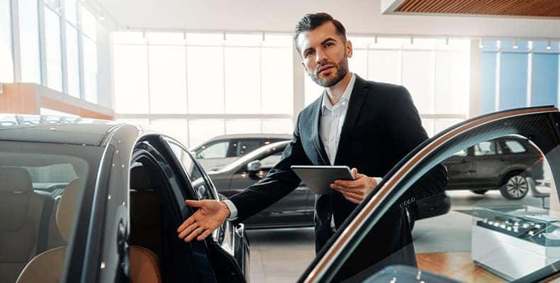 The Advantages of Buying a Car from a Dealership vs. a Private Seller. Learn more at Stetler DCJR in York, PA | Salesman showing new car inside of dealership