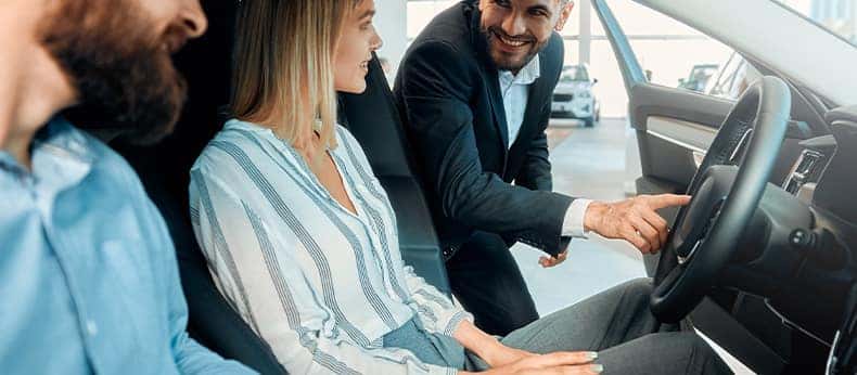 The Advantages of Buying a Car from a Dealership vs. a Private Seller. Learn more at Stetler DCJR in York, PA | Customers sitting in new car while salesman shows them the car features