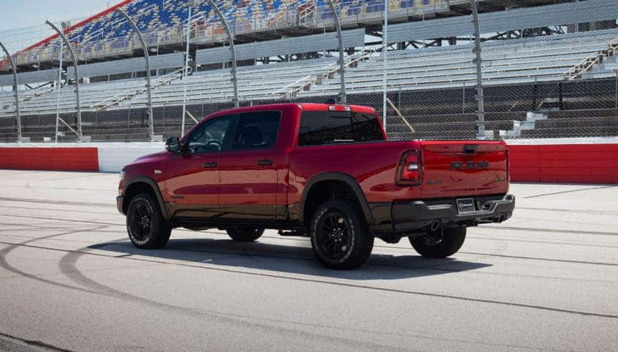 A side view of a red RAM 1500 on a race track.