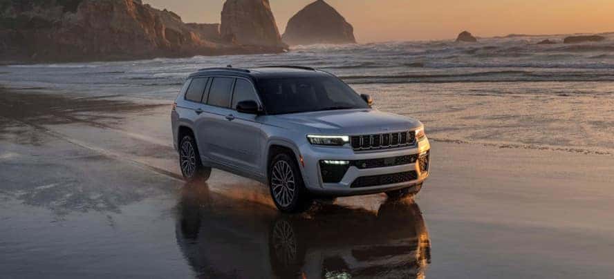 A silver Jeep Grand Cherokee driving on the beach.