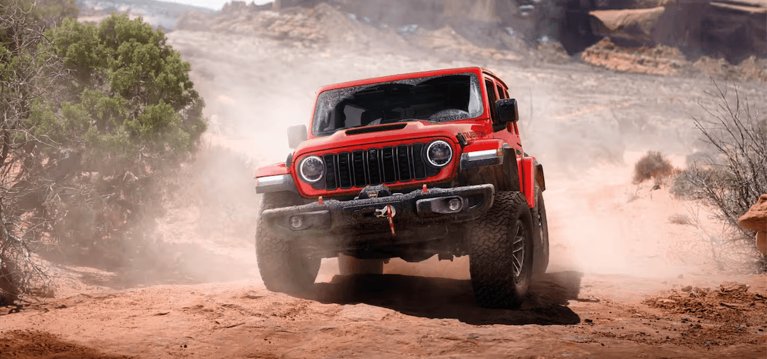 Front view of a red 2027 Jeep Wrangler on a dirt road