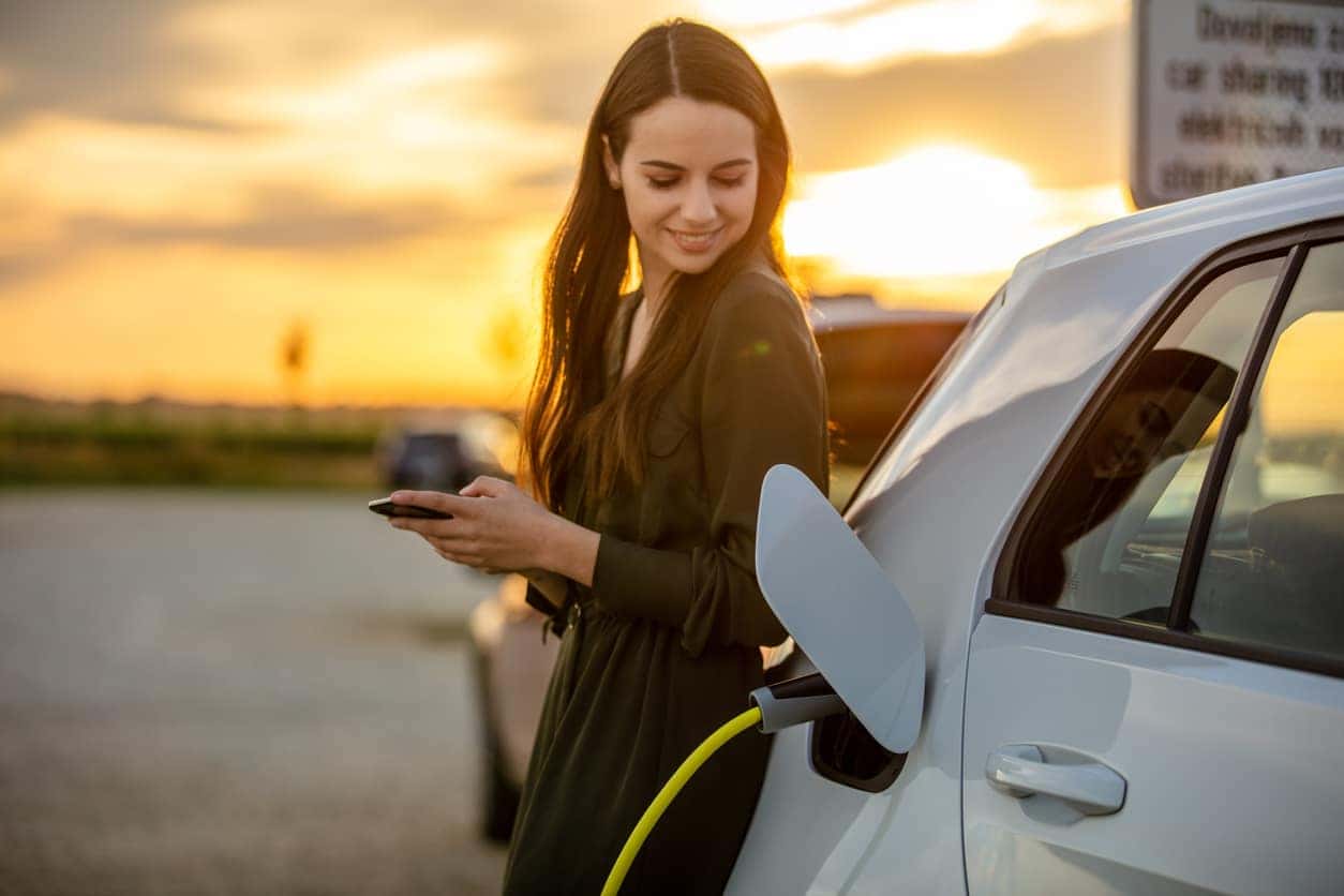 Young woman charging her electric vehicle at an EV charging station