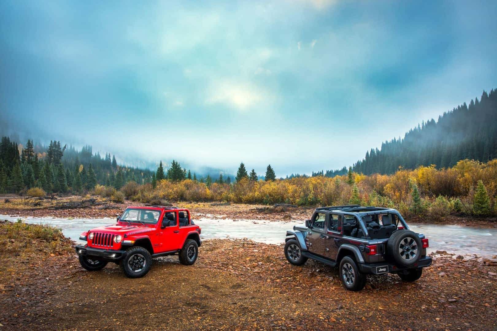 Two Jeep Wranglers on the bank of a river