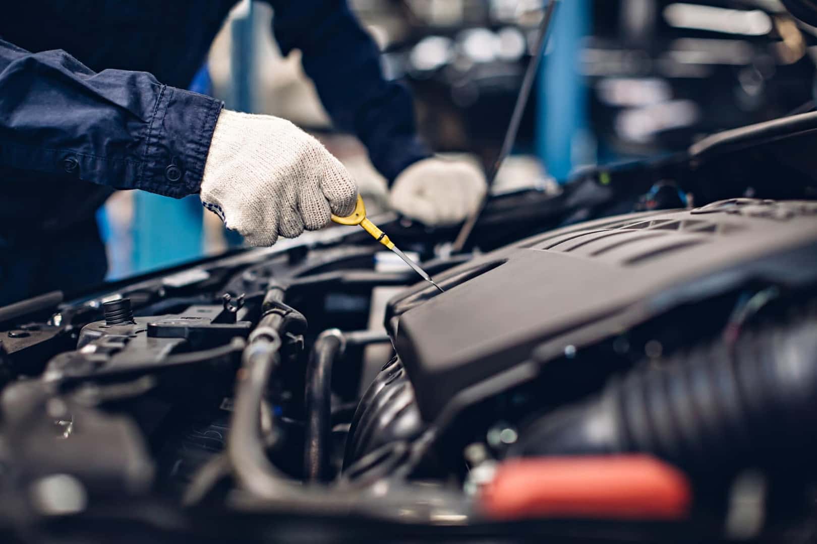 Service technician checking oil under car hood