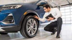 Buick Certified Service Advisor checks out the tires on a maintenance inspection