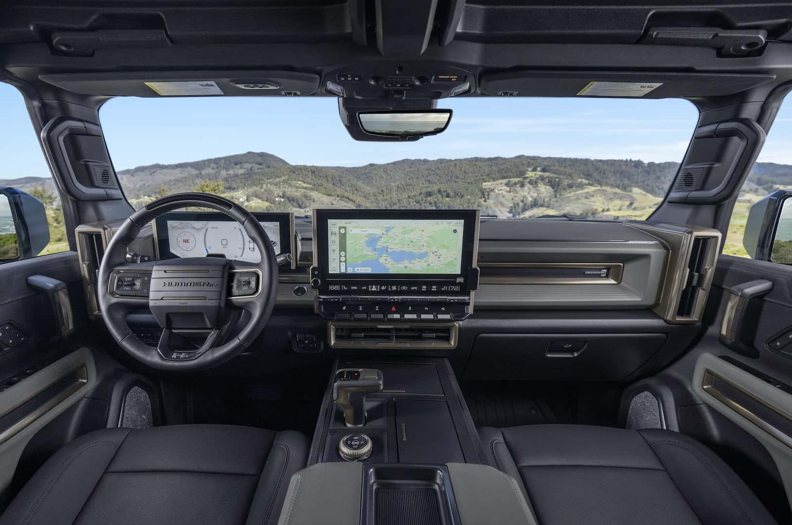 Front seat view of Lunar Shadow interior in the 2024 GMC HUMMER EV SUV overlooking mountain vista.