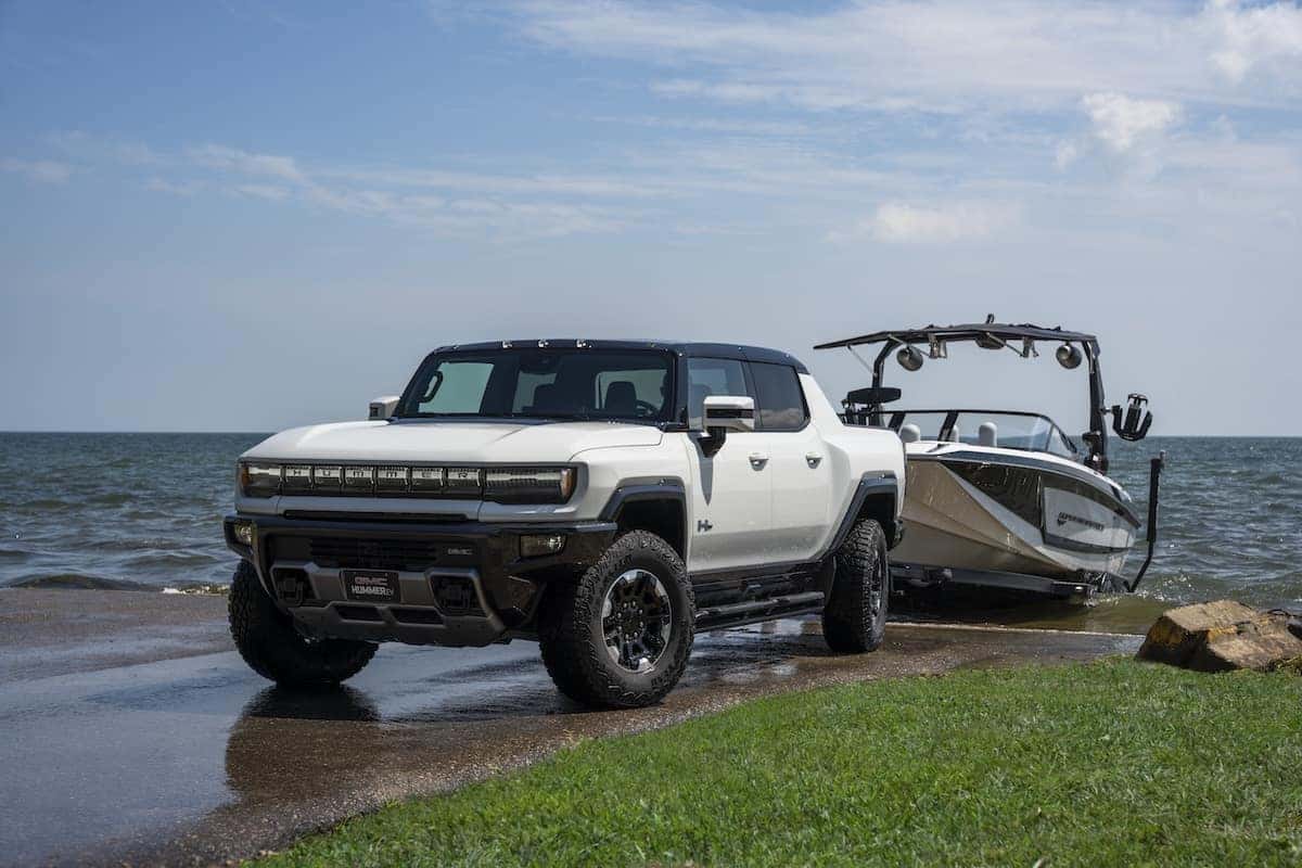 Front 7/8 view of the 2023 GMC HUMMER EV Edition 1 Pickup launching a Super Air Nautique GS22E electric boat into the water.