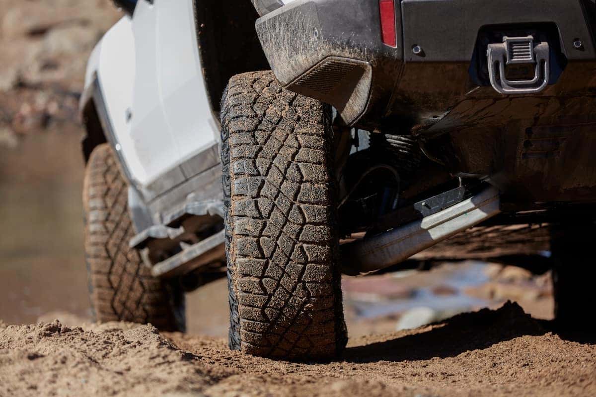 Detail shot of the 2023 GMC HUMMER EV Edition 1 Pickup tires on a dirt road. The 2023 HUMMER EV Edition 1 Pickup builds upon GM’s Continuous Damping Control with Adaptive Ride Control technology and can “read” the road every 2 milliseconds.