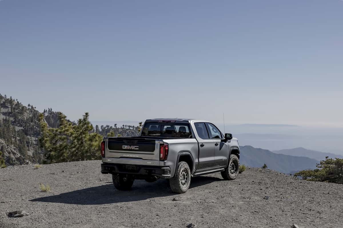 2024 GMC Sierra 1500 AT4X AEV Edition Crew Cab Short Box in Sterling Metallic; 3/4 passenger-side rear parked on a mountain top.