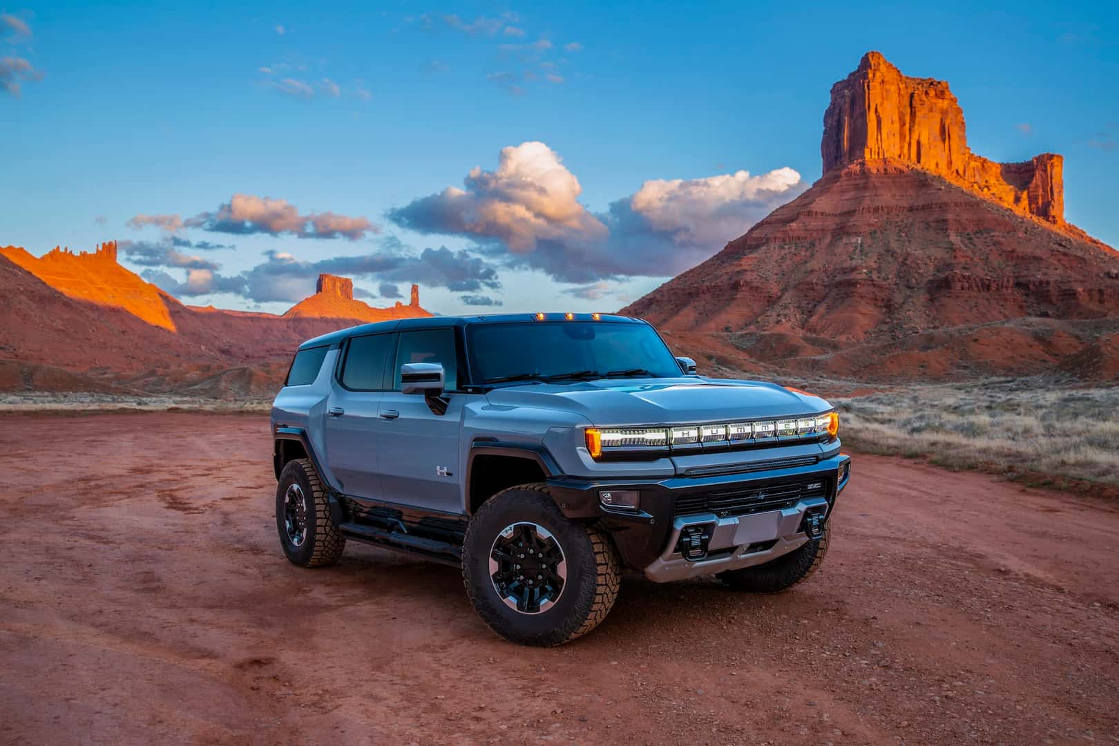Front passenger 3/4 view of 2024 GMC HUMMER EV SUV 3X in Meteorite Metallic as sun sets.