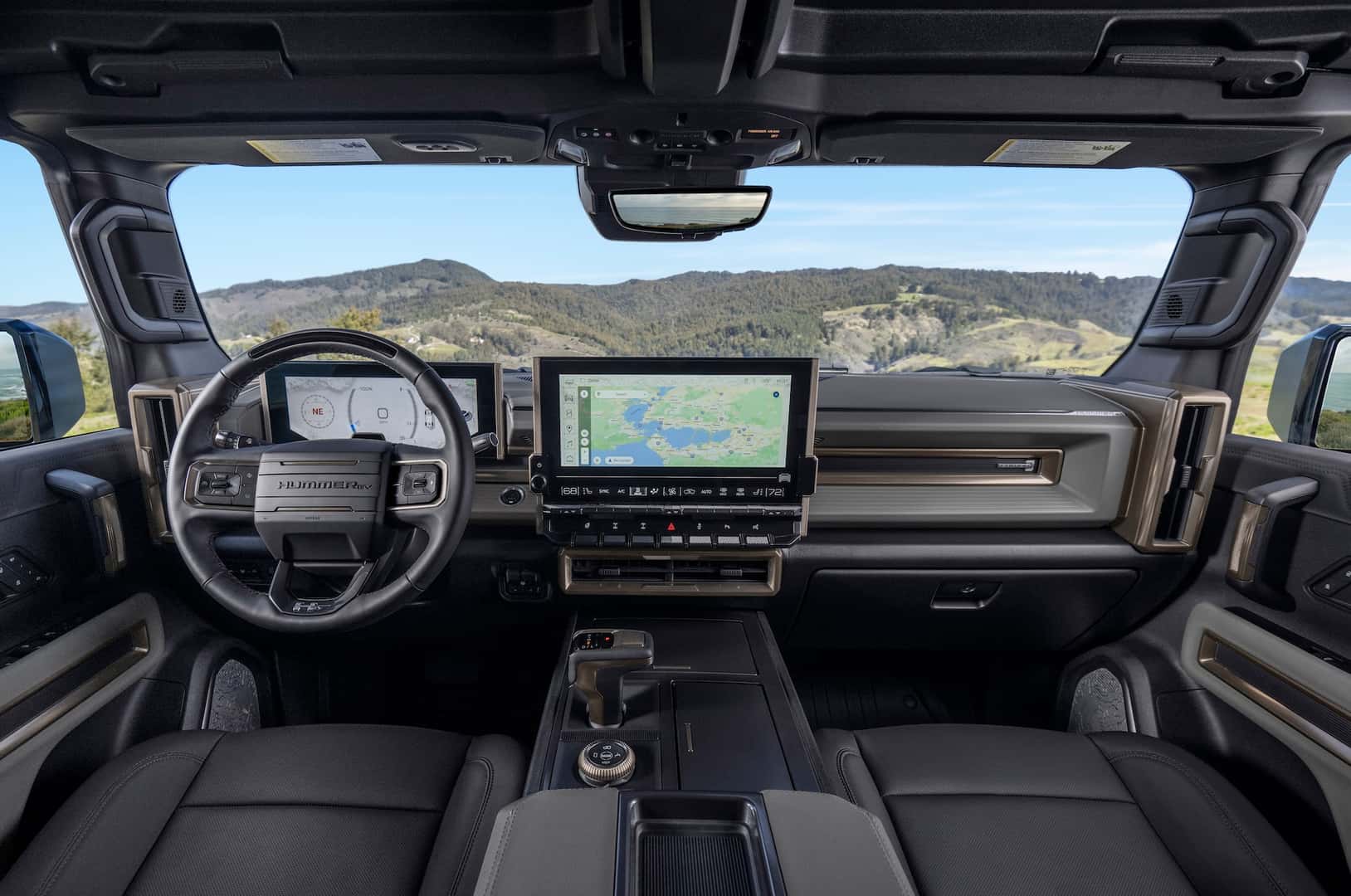 Front seat view of Lunar Shadow interior in the 2024 GMC HUMMER EV SUV overlooking mountain vista.