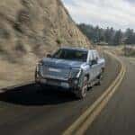 Front shot of the 2025 GMC Sierra EV Denali in Moonlight Matte driving on mountain road.