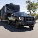 Front 3/4 view of the 2024 GMC Sierra 2500 HD Denali Ultimate towing a trailer