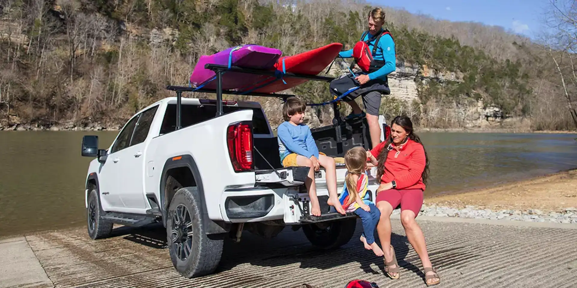 2026 GMC Life Adventure Truck Bed with accessories, kayaks and a family by a lake