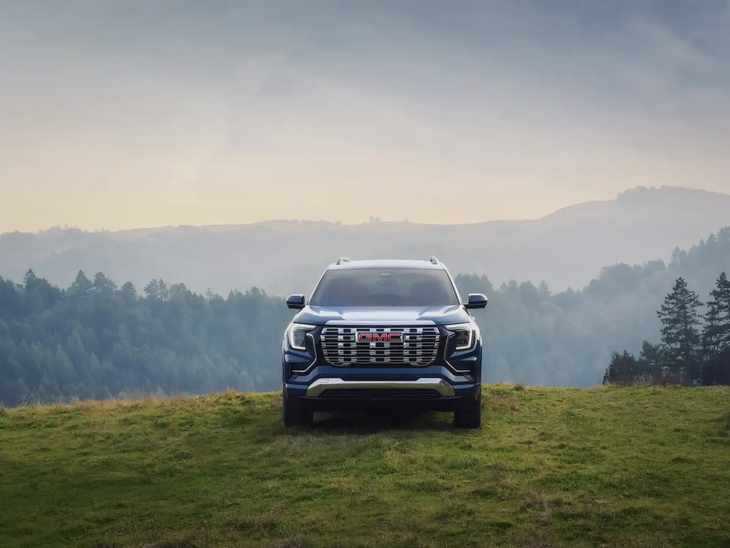 2026 GMC Terrain Denali view of the front parked off road with mountains in the back