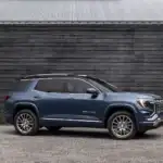 2026 GMC Denali view of the side profile parked on a gravel lot in front of a fence