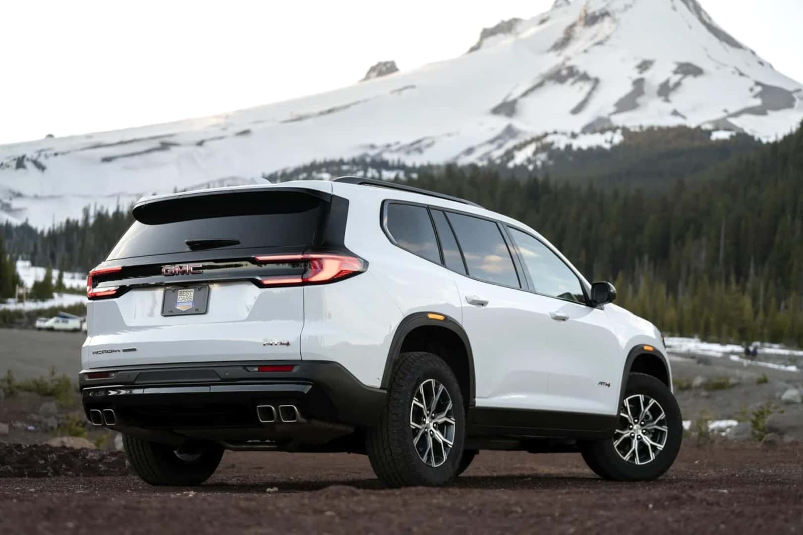 The Fancy And Refined Rear Exterior Of The Sparkling GMC Acadia, Parked In A Valley In View Of A Snow-Capped Mountain