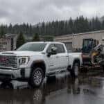 2026 GMC Sierra HD Crew Cab with equipment trailer in Auburn, WA industrial corridor under overcast Pacific Northwest sky