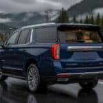 2026 GMC Yukon parked on a wet road in Auburn, WA with evergreen hills in the background