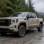 2026 GMC Sierra AT4 on a wet gravel forest road in Western Washington surrounded by evergreen trees
